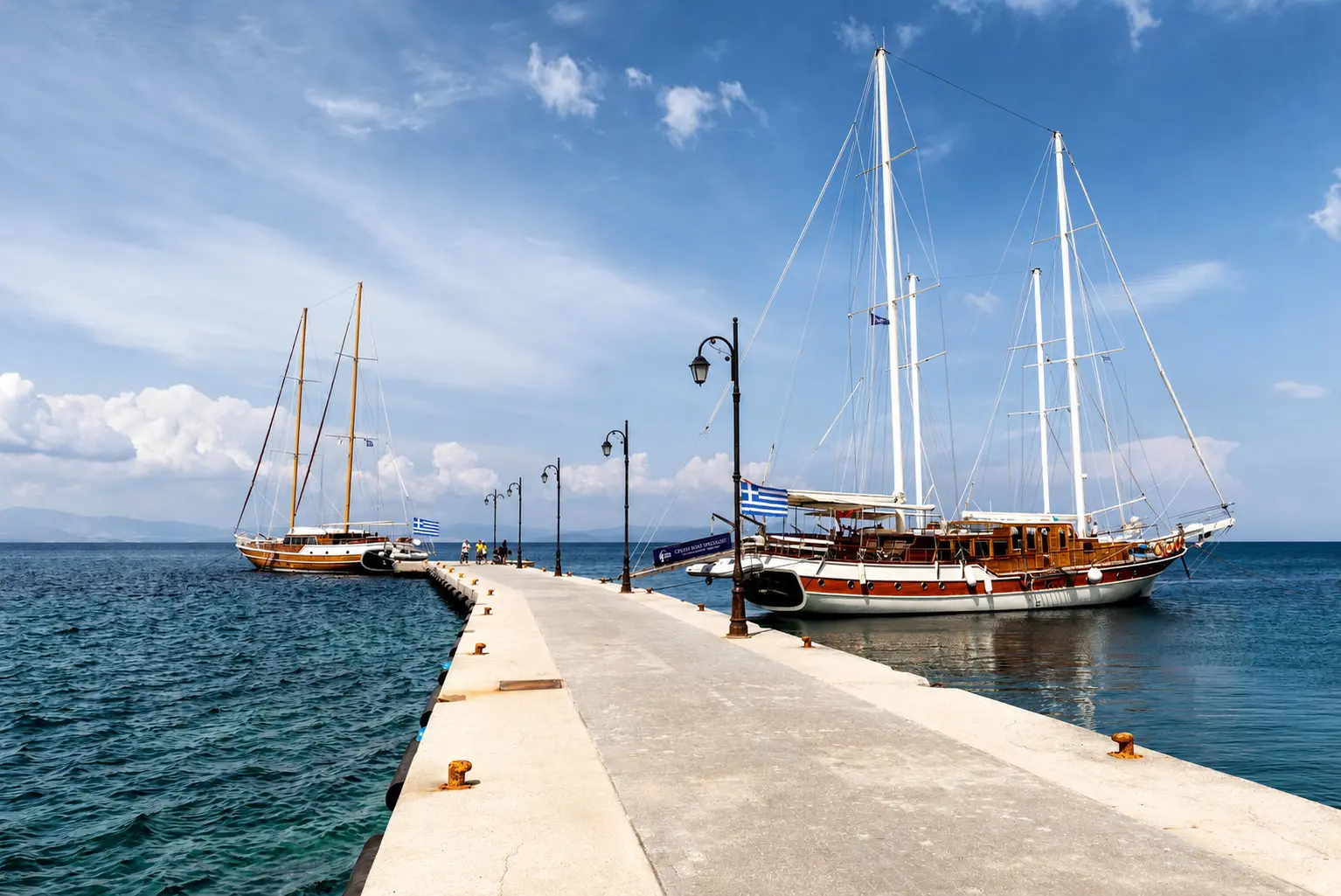 A day cruise boat anchored off a Saronic Gulf island with swimmers in turquoise water