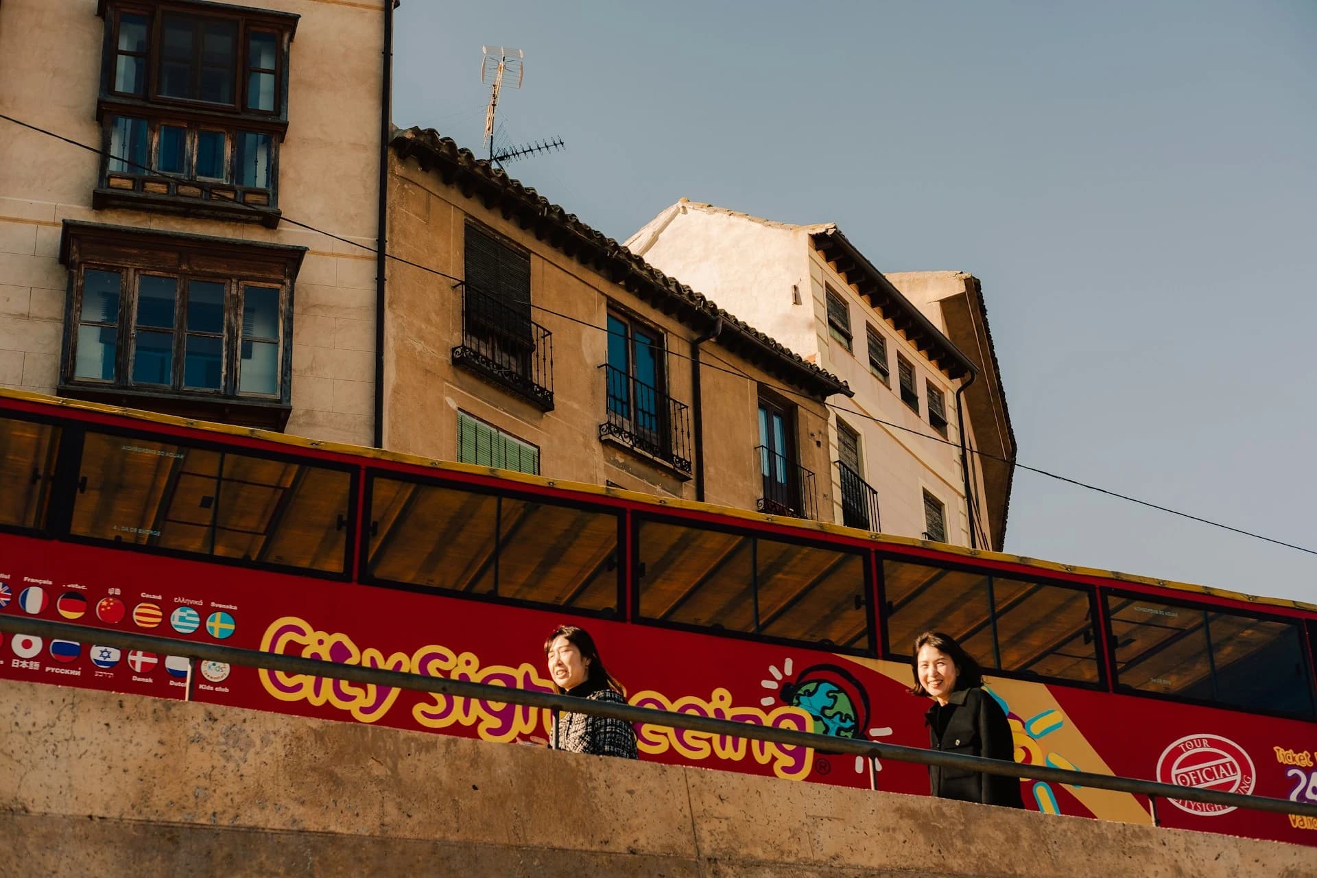 A red open-top double-decker sightseeing bus passing the Greek Parliament on Syntagma Square in Athens