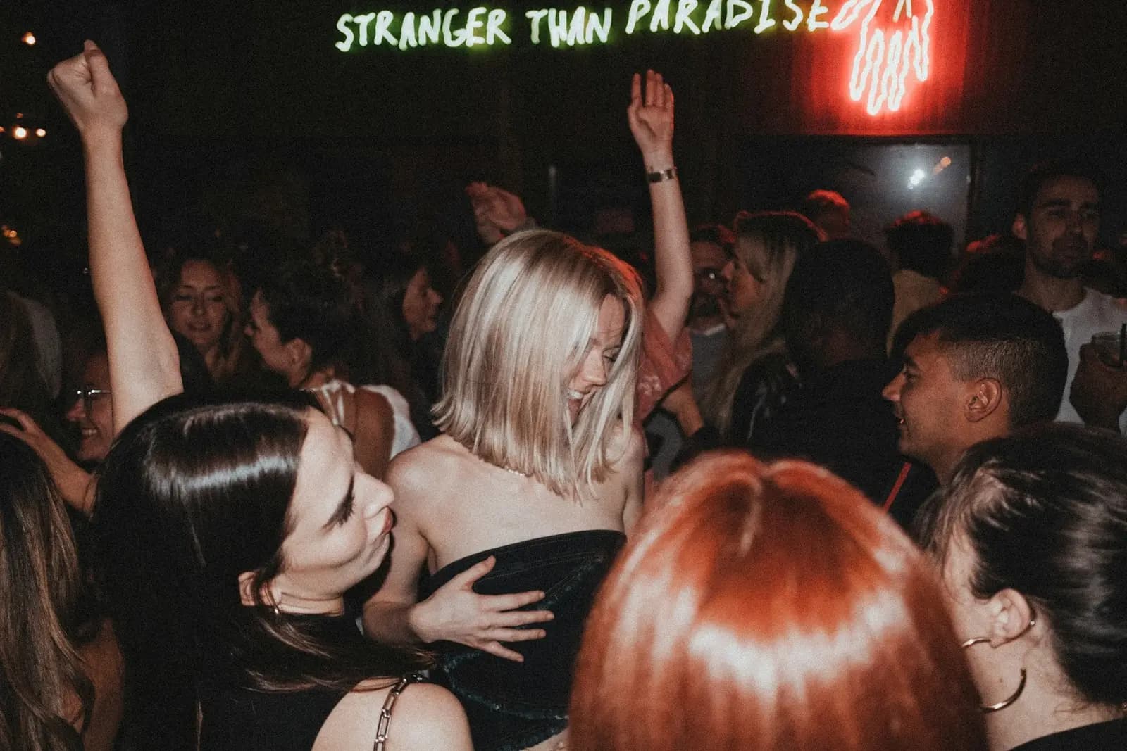 A group toasting with shots at a busy bar in the Psyrri nightlife district of Athens