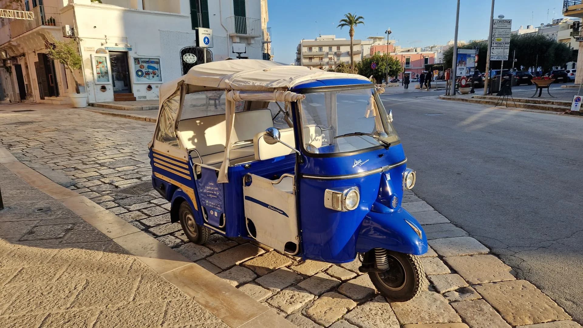 Open electric tuk-tuk with passengers driving past the Parliament building on Syntagma Square in Athens