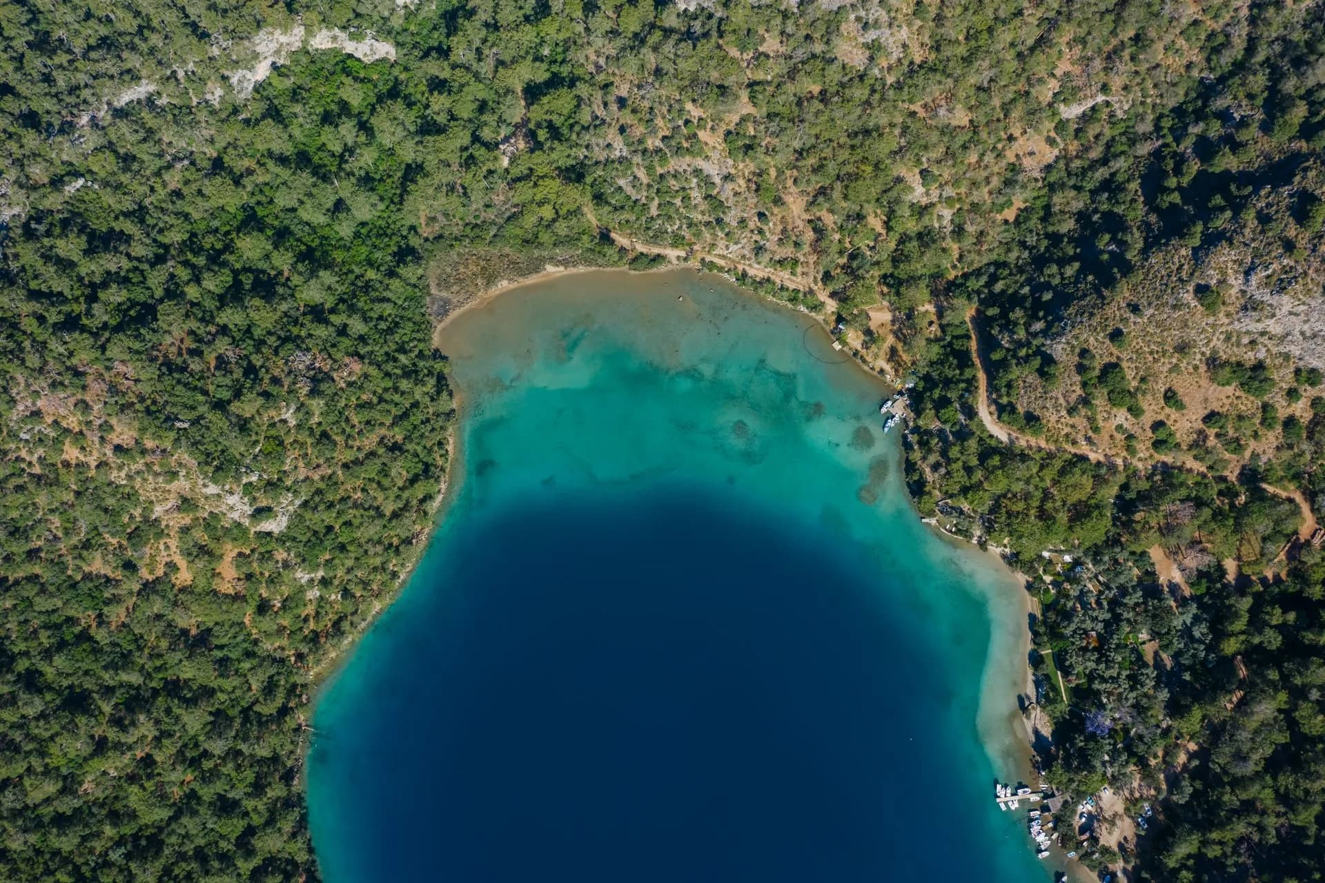 Swimmers in the turquoise water of Lake Vouliagmeni below a limestone cliff on the Athens Riviera