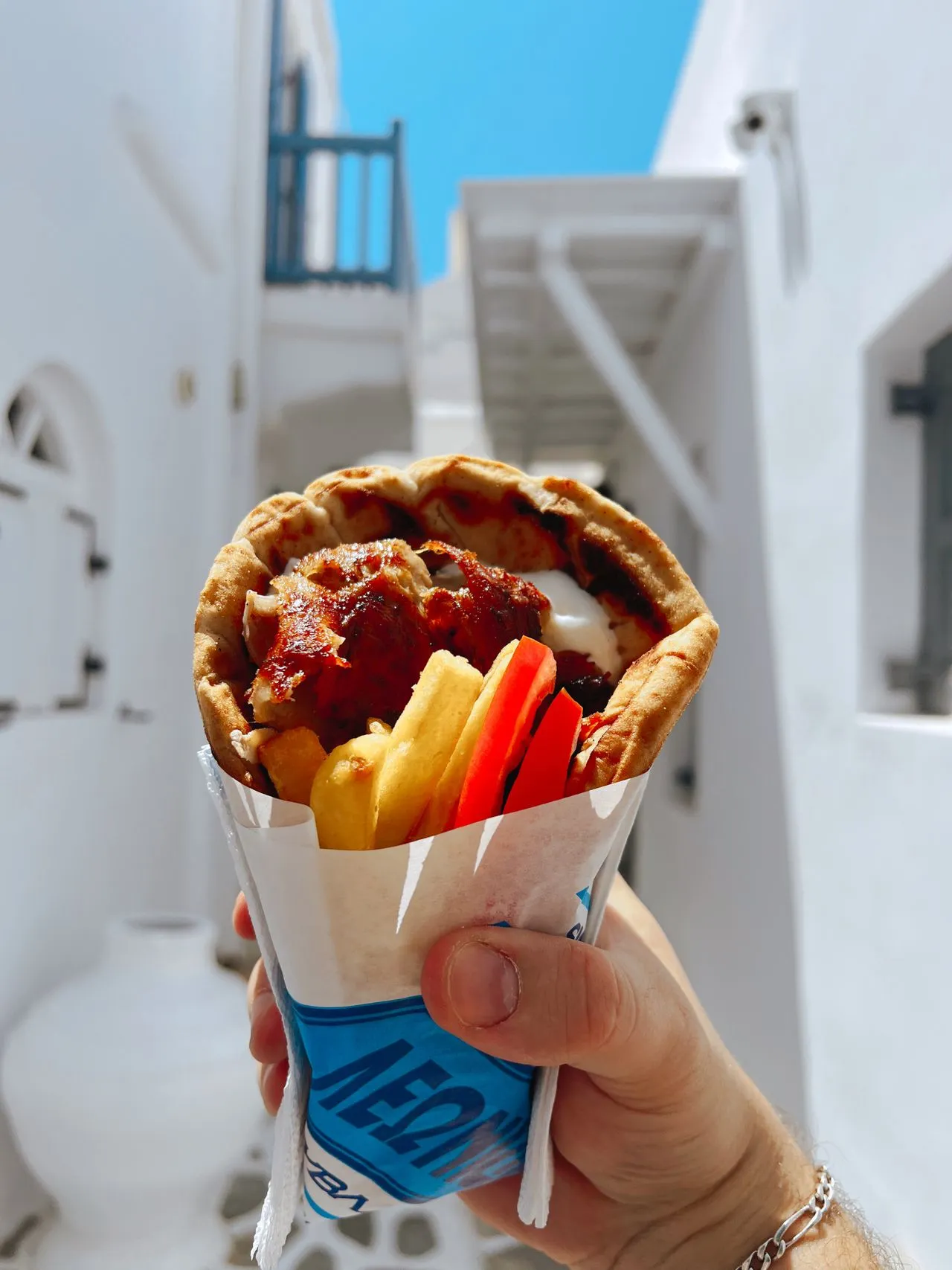 A Greek gyro wrapped in pita with fries and salad, a classic Athens street food