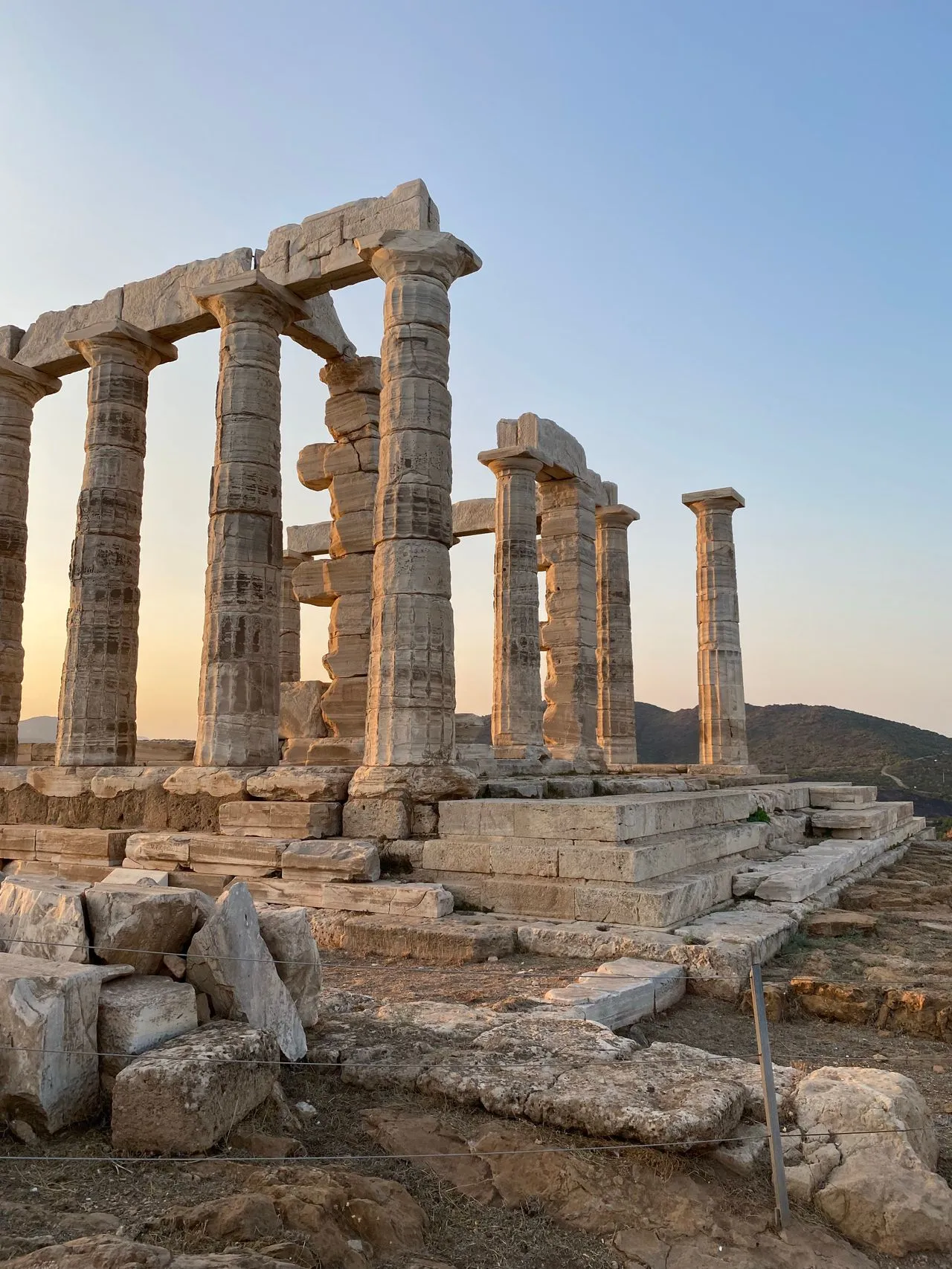 The Doric columns of the Temple of Poseidon at Cape Sounion silhouetted against the Aegean at sunset